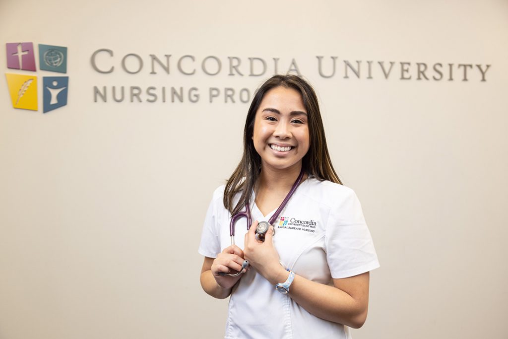 Concordia St. Paul ABSN student standing in front of university logo