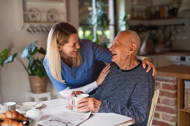 nurse in elderly patient's home smiling with patient