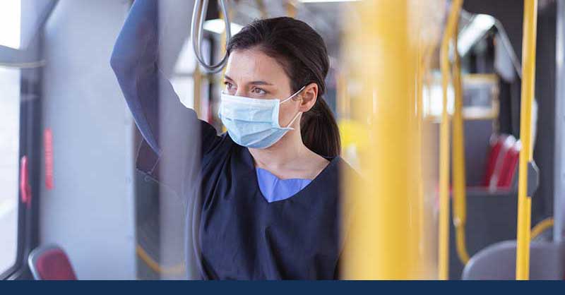 nurse wearing face mask standing in public transit